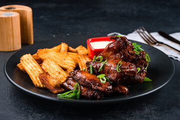 Snack for beer chicken wings with potato chips, green onions and sauce.