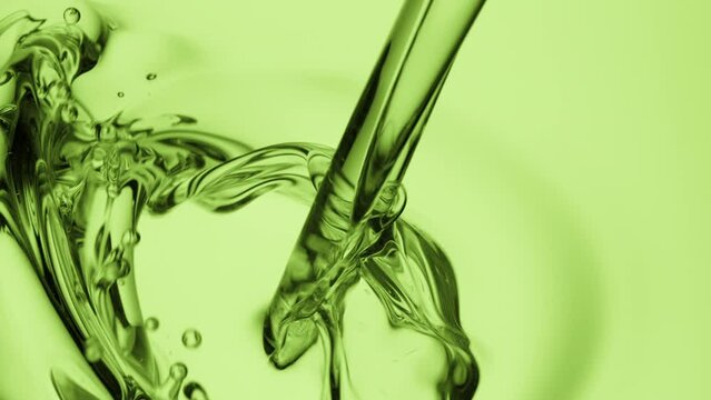 Macro crane shot of hemp oil is being poured into green oil on green background | Abstract skin care cosmetics ingredients formulating concept
