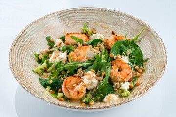 Fresh salad with shrimp, quinoa, arugula, spinach, cucumbers, cream cheese, pine nuts and dressing.