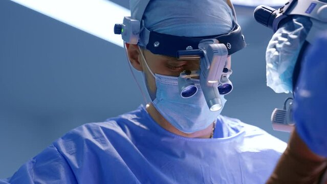 Surgeon’s co working at operation. Doctors with device glasses on heads performing surgery. Close up.