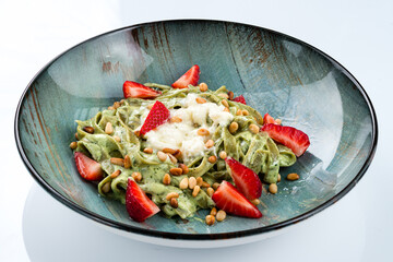 Green pasta Linguini with spinach, pine nuts, strawberries, sauce.