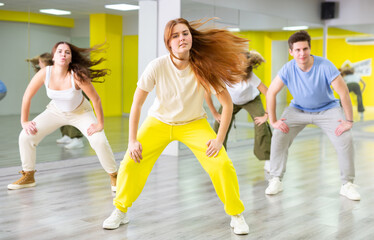 Fototapeta na wymiar Group of positive teenagers dancing modern dance in ballroom