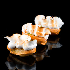 Fototapeta na wymiar Sweet mini eclairs with pistachio and seared meringue.