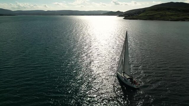 Aerial of sun yacht sail in agean sea. White boat at open sea. Summer cruise on sailboat at sunlight with clouds. urla izmir sea coast with water transport. . High quality 4k footage