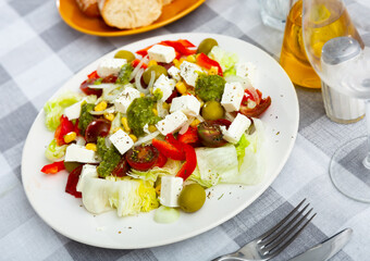 Corn, lettuce, pepper, olives, onion, cheese, tomato and pesto sauce served on plate and ready-to-eat.