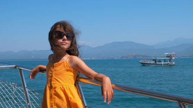 Happy child on yacht nose. A happy ittle girl pass her time on yacht nose during sea trip in summer.