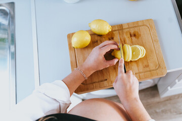 unrecognizable pregnant woman cutting lemons