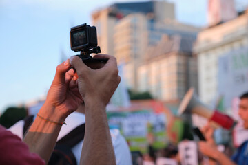 Unrecognizable person filming with an action camera during an environmental protest, the Global Climate Strike