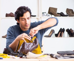 Young man repairing shoes in workshop