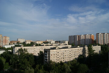 Fototapeta premium Multi-storey houses in a big city at sunset. Cloudy sky. The sun is shining on the houses.
