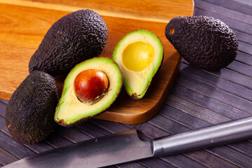 Ripe juicy avocado lying on a cutting board on a wooden surface. Ingredients for cooking