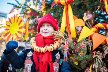 smiling boy at the traditional Russian festival dedicated to the meeting of spring, the week of pancakes, Shrovetide. the child stands at the decorations for the Maslenitsa holiday