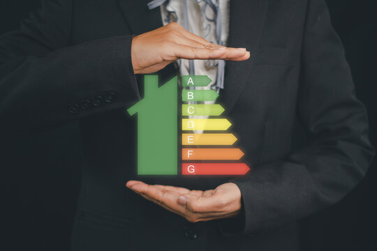 Business woman hand holding house icon energy efficiency scale image on virtual screen, Concept of ecological and bio energetic house. Energy class..