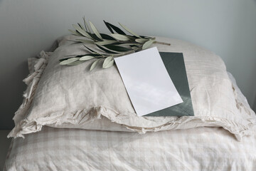 Fluffy beige linen, cotton gingham pillows. Green olive tree branches. Pile of checkered cushions. Greeting card, invitation mockup i sunlight. Blurred feminine still life background. Sleeping concept