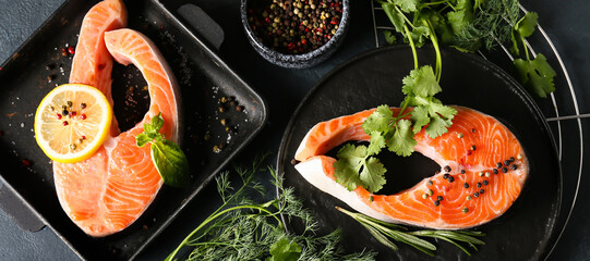 Raw salmon steaks, herbs and spices on dark background, top view