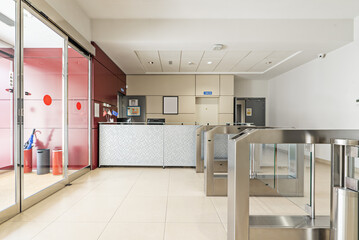 Entrance to an office building with access control with glass doors with key cards, empty reception desk and automatic glass doors