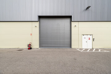 Retractable metal gate on the facade of an industrial warehouse with security cameras