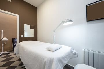 Room in an aesthetic medicine center with a stretcher to lie down and apply treatments and a magnifying lamp for intense lighting