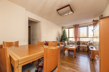 Living room of a house with folding cherry wood furniture, matching chairs, a sofa with many cushions and an oak floor