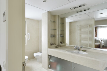 Large luxurious modern style bathroom with a large cream marble countertop with a sink, tempered glass doors and a large built-in mirror on the wall