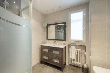 Bathroom with rectangular white resin sink on a dark wood cabinet with tempered glass drawers and mirror with matching wood frame