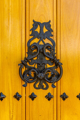 iron knocker on a yellow wooden door