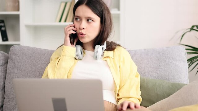 Nervous stressed young caucasian woman freelancer typing quickly on laptop computer and looking at screen ignoring phone ring asking to hurry up and worrying about deadline at home