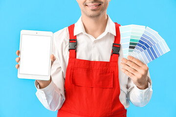 Male painter with color palettes and tablet computer on blue background, closeup