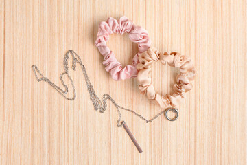 Stylish scrunchies and necklace on wooden background