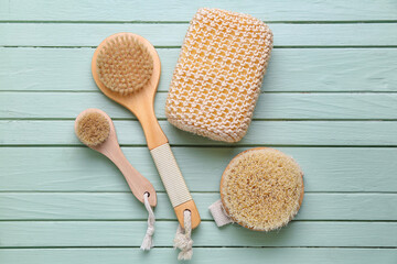 Fototapeta na wymiar Massage brushes and bath sponge on color wooden background