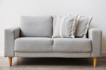 Soft pillows on sofa near light wall