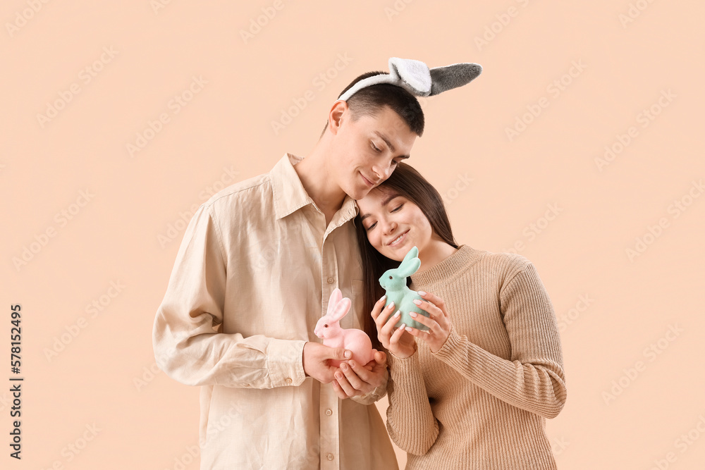 Sticker happy young couple in bunny ears with easter rabbits on beige background