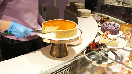orange cheesecake on display in a cafe. the chef cuts a piece of cheesecake