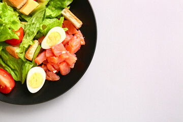 Plate of delicious salad with boiled  eggs and salmon on grey background