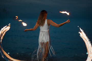 Caucasian woman dancing with fire in the water. Fire show at sea. Acrobatics on the beach. Yoga and relaxation at sunset. Spectacular circus performance. model body. High quality FullHD footage.  © aaalll3110