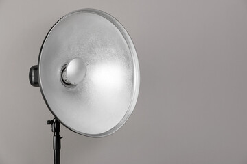 Professional beauty dish reflector on tripod against grey background, space for text. Photography equipment