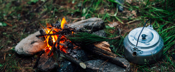 Camping kettle near small camp fire close-up. Cozy camping place in wild. Wonderful evening atmospheric background of campfire. Beautiful flame of small magic bonfire. Romantic warm place with fire.