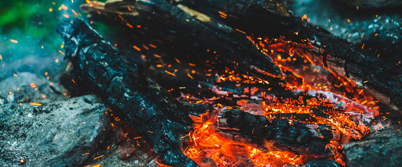 Vivid smoldered firewoods burned in fire closeup. Atmospheric background with orange flame of...