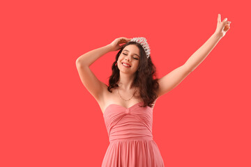 Teenage girl in tiara and prom dress on red background