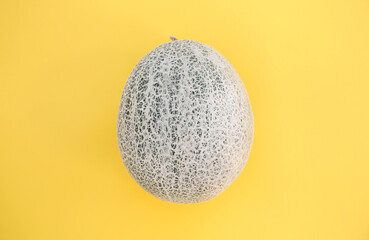 Whole fresh ripe cantaloupe melon on yellow background, top view