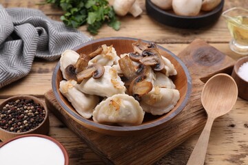 Delicious dumplings (varenyky) with potatoes, onion and mushrooms served on wooden table