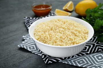 Bowl of tasty couscous on grey table, closeup