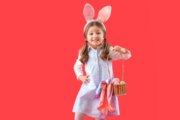 Cute little girl in bunny ears with basket of Easter eggs on red background