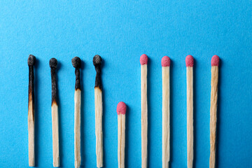 Burnt and whole matches on light blue background, closeup. Stop destruction by breaking chain...