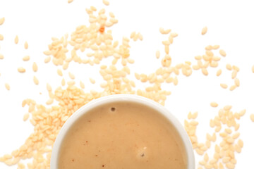 Bowl of tasty tahini and sesame seeds isolated on white background, closeup