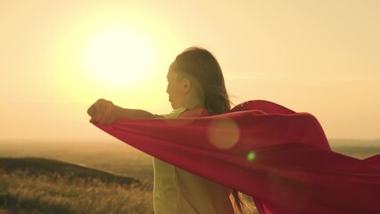 girl superhero sunset glare. game teenager red raincoat top mountain. glare sun sky. brave...