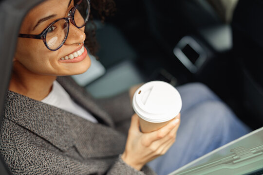 Smiling Woman Passenger In Eyeglasses Drinking Takeaway Coffee In Taxi Car On The Way To Work