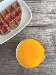 Breakfast of waffle chocolate with strawberry jam and orange juice
