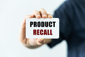 Produc recall text on blank business card being held by a woman's hand with blurred background. Business concept about product recall.