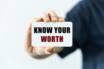 Know your worth  text on blank business card being held by a woman's hand with blurred background. Business concept about knowing your worth.